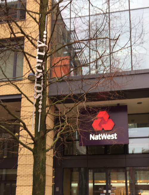 words "...so sorry" installed in a tree outside a branch of the Nat West